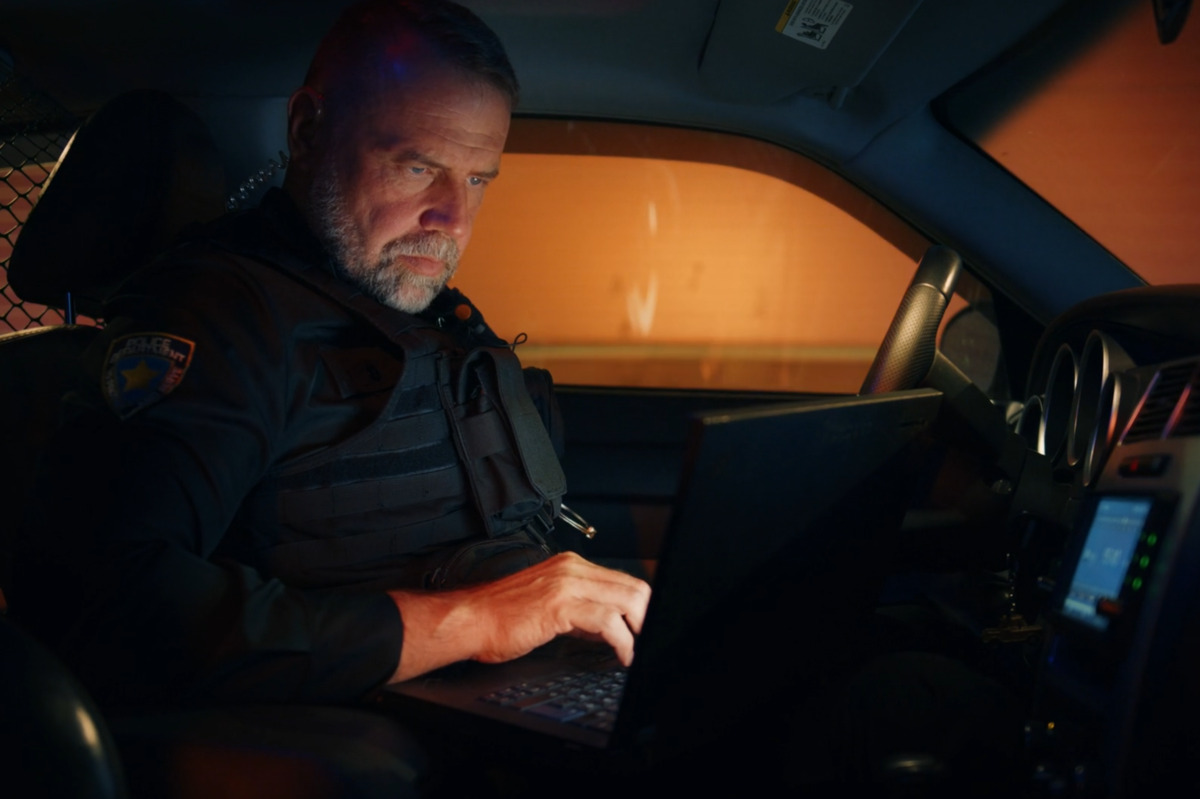 A policeman working on a laptop inside a patrol car